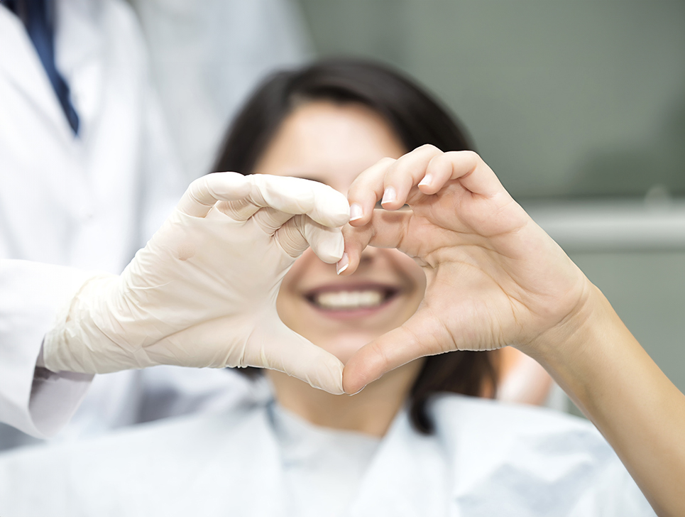 A doctor and patient holding their hands together in the shape of a heart.