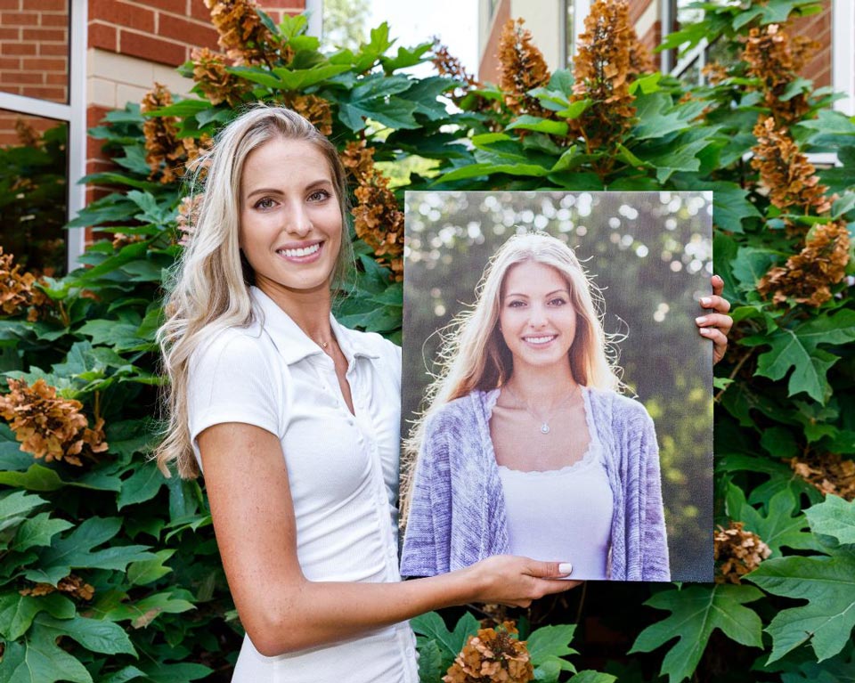 Woman who has finished orthodontic treatment holding a picture of herself prior to treatment