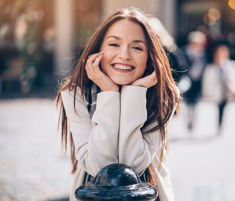 Woman with clear braces in Waterford, CT smiling downtown on an autumn afternoon