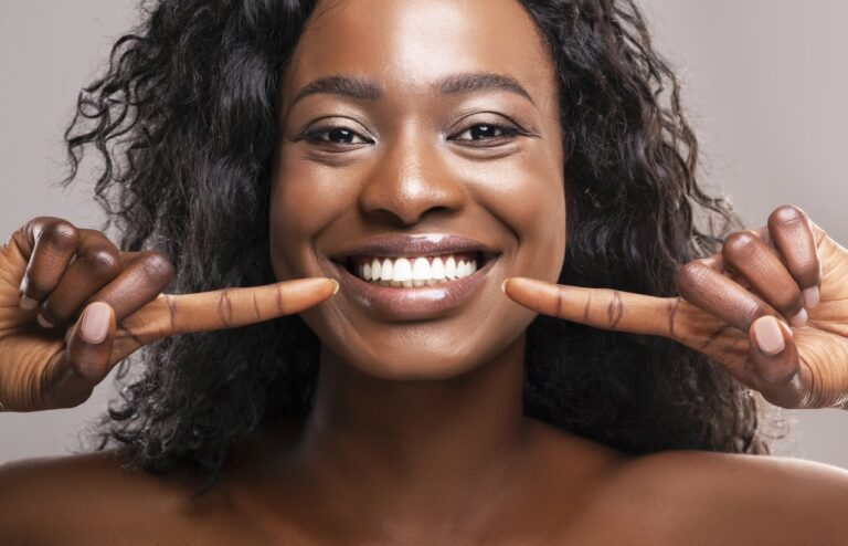 Happy Black Woman Pointing At Her Perfect White Teeth
