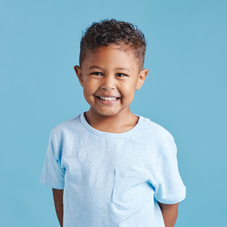 Adorable kid with short curly hair smiling in a sky blue shirt